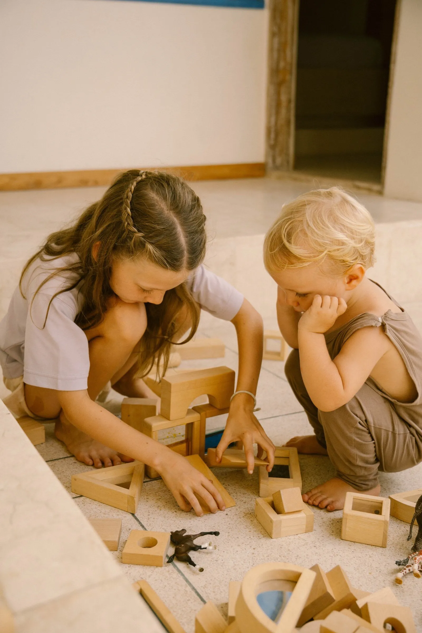 Two children building with wooden blocks on the floor