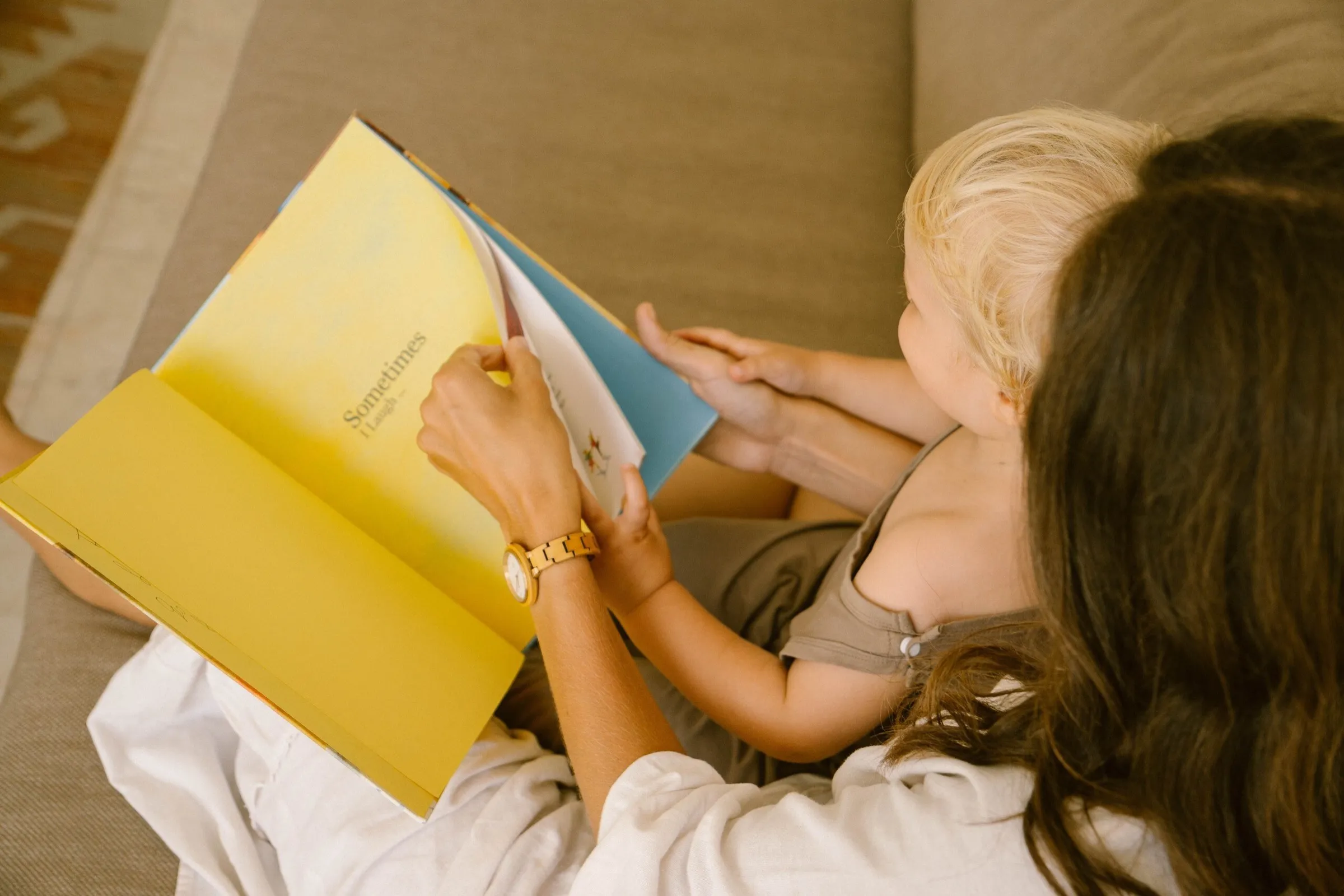 A mother and child reading the book, its yellow cover open